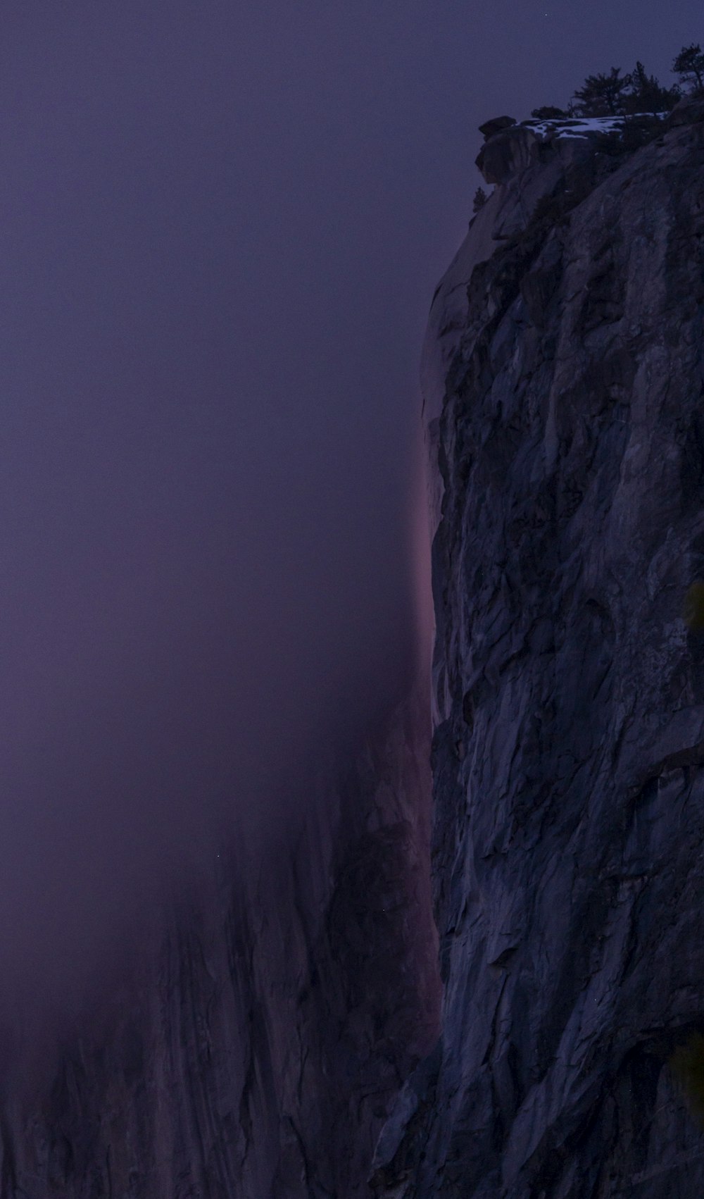 a foggy mountain with a tall rock face