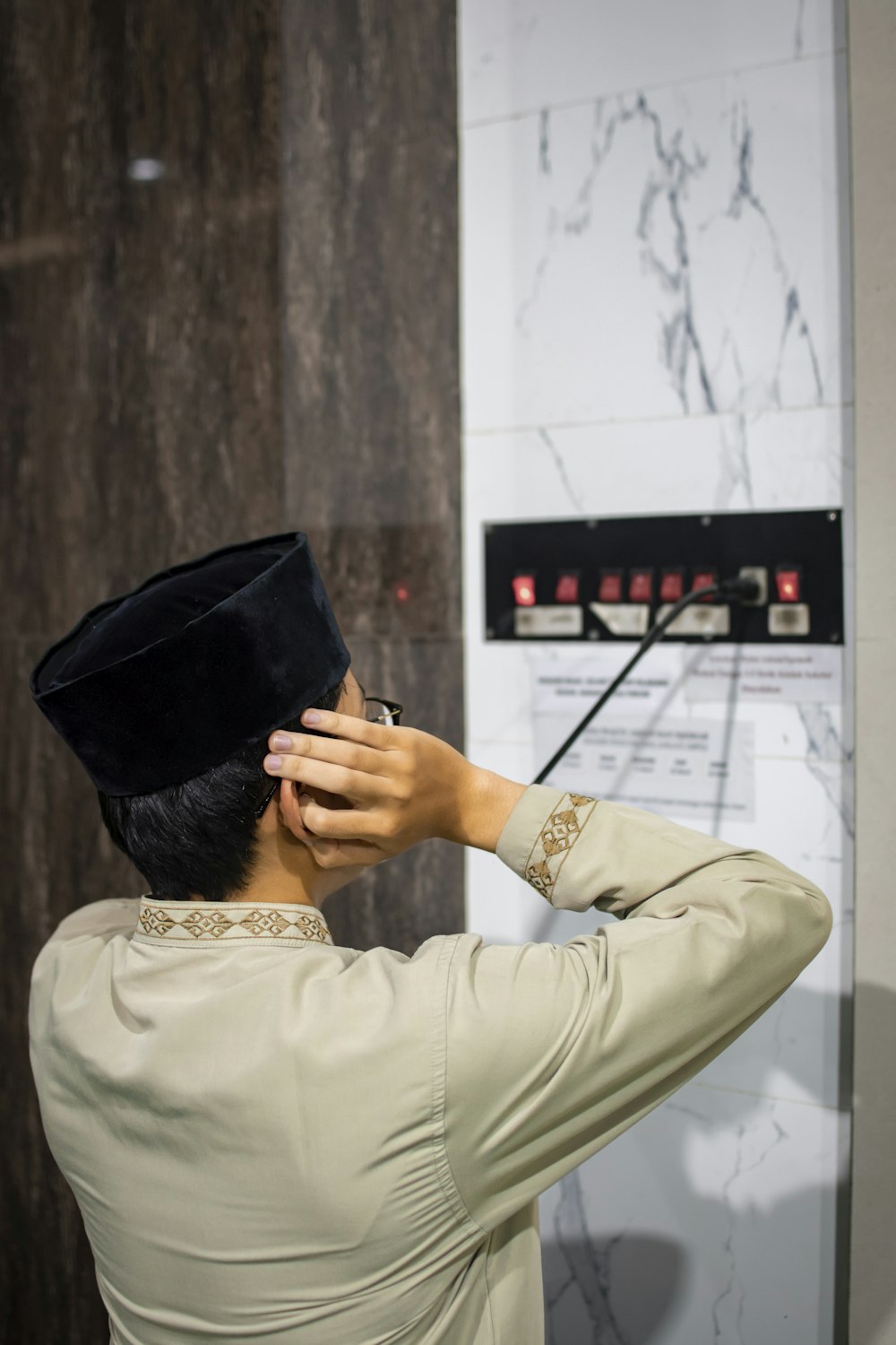 a man in a black hat standing in front of a wall