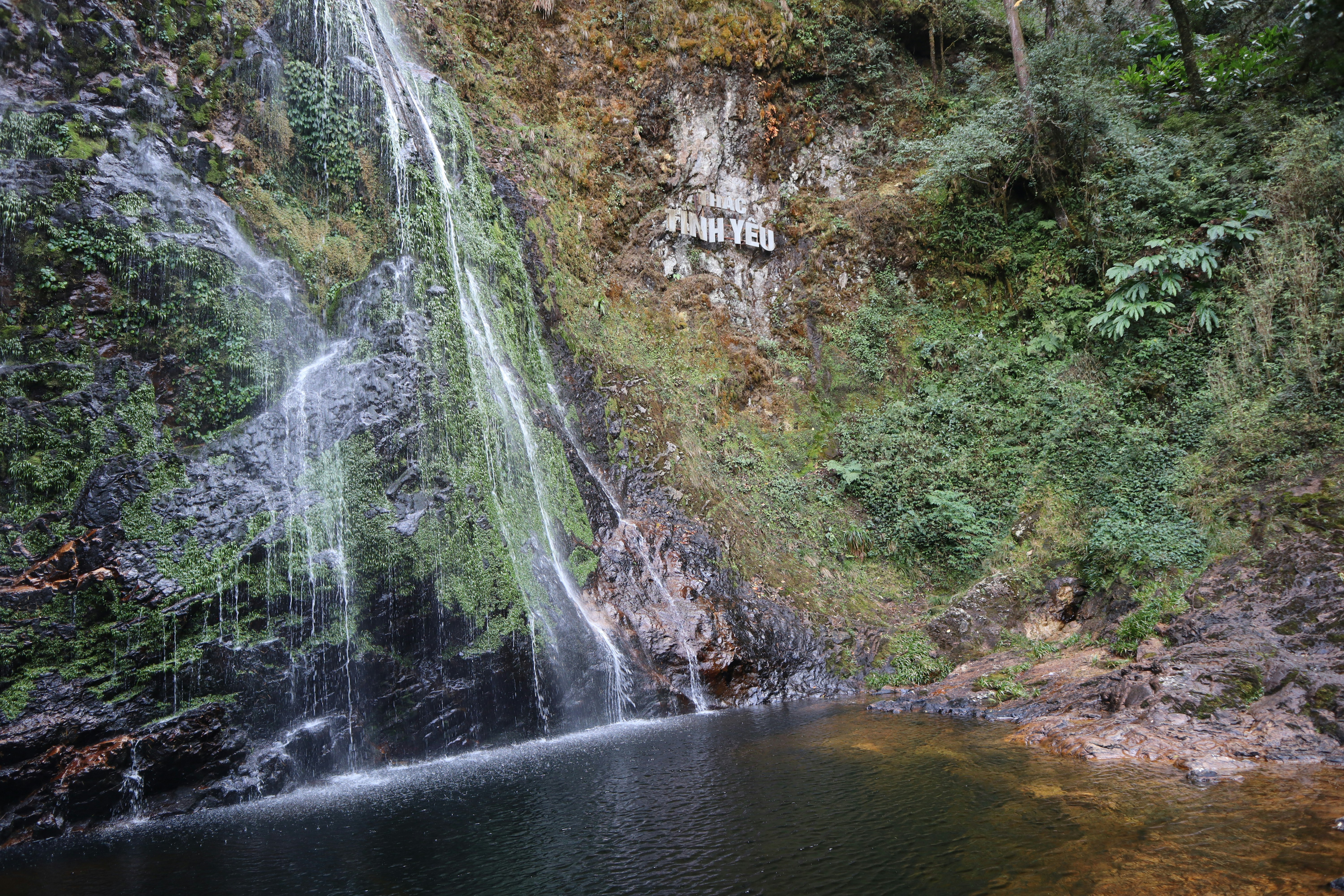 a waterfall with a sign on the side of it