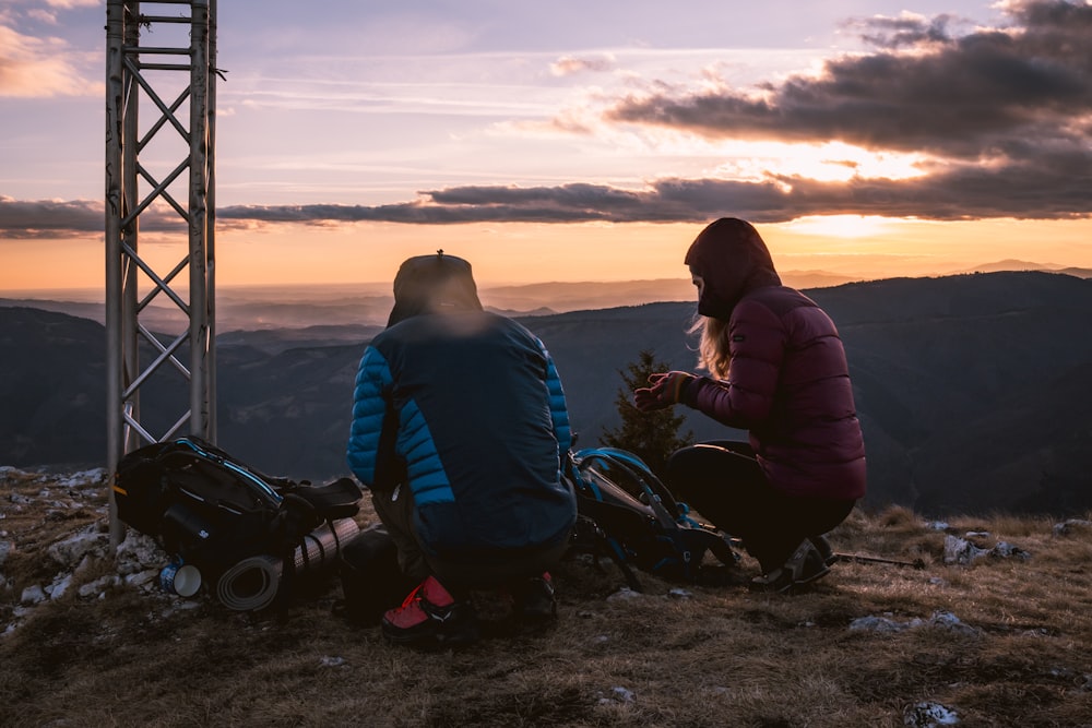 a couple of people sitting on top of a mountain