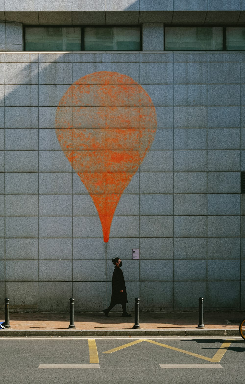 a person walking down a street past a building with a large orange balloon painted on