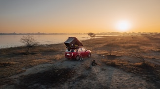 A cozy car interior at sunset with a wildrise air mattress set up, surrounded by forest scenery.