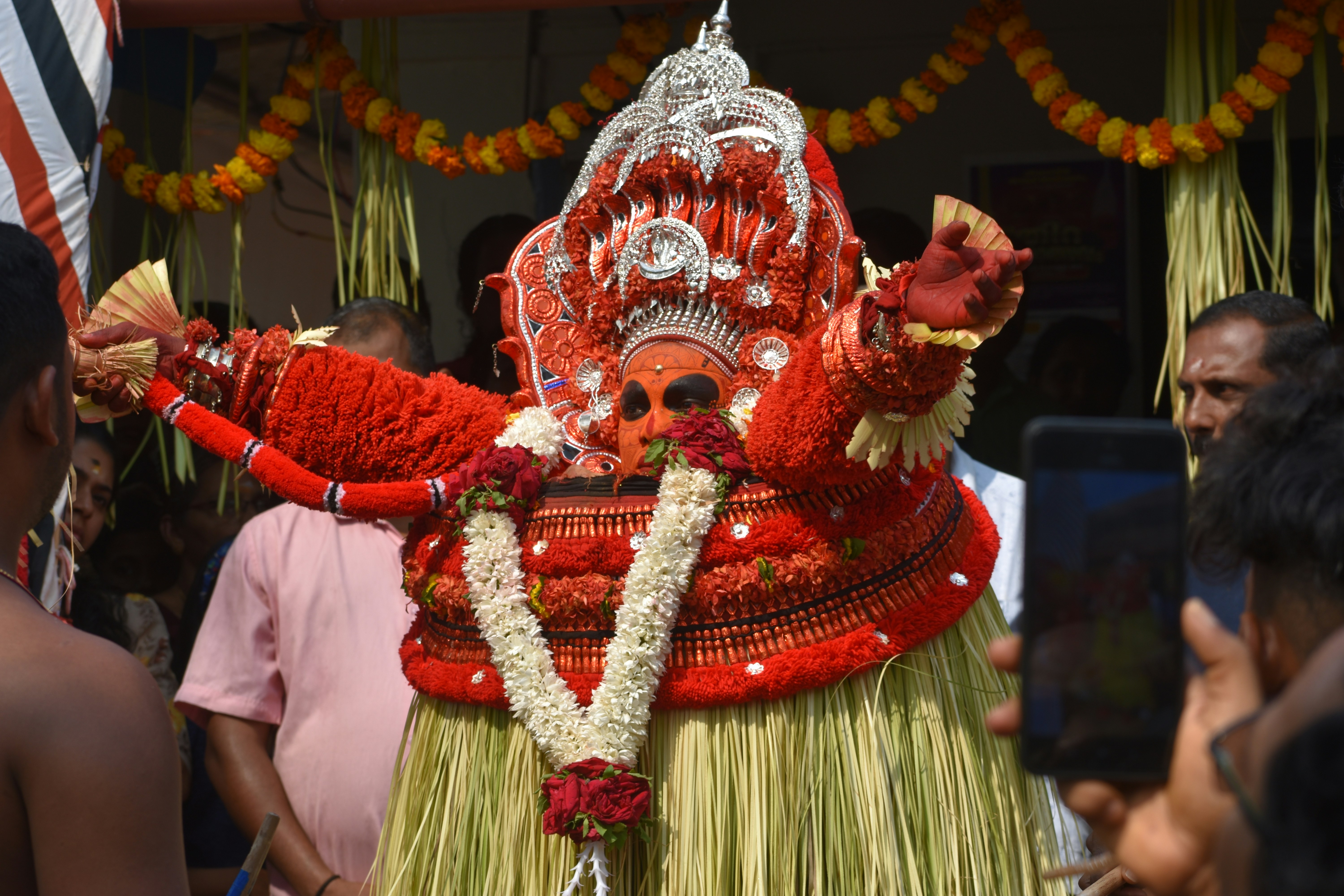 a man dressed in a red and green costume, Theyyam is a Hindu ritualistic dance form practised in northern Kerala. Theyyam consists of traditions, rituals and customs associated with Malabar