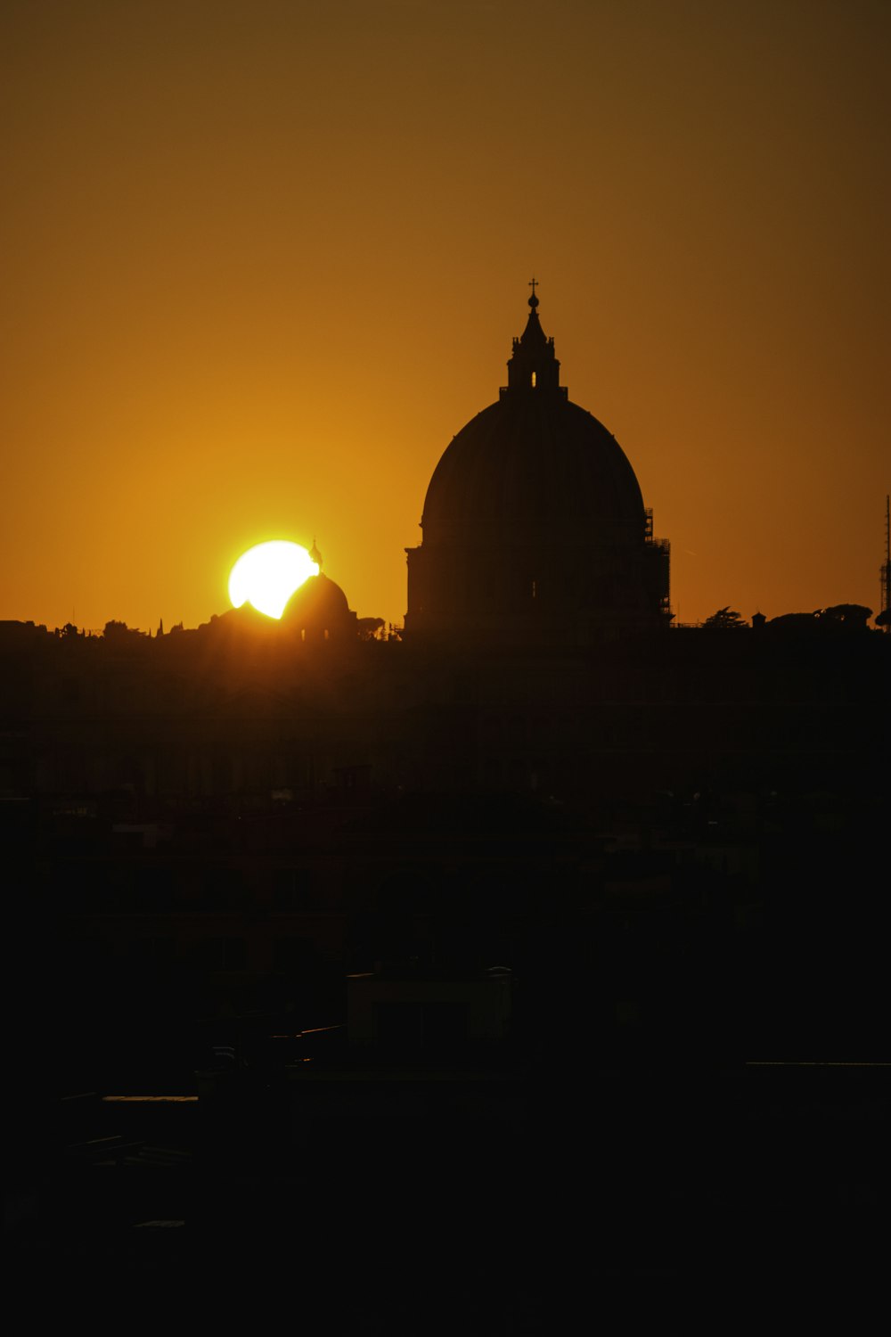 the sun is setting behind a building with a dome