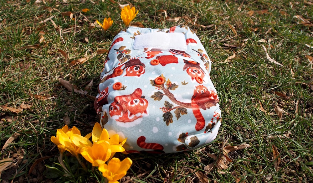 a cloth diaper sitting in the grass next to yellow flowers