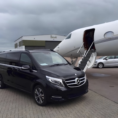 A sleek black Mercedes Vito VIP vehicle parked in front of a modern airport terminal.