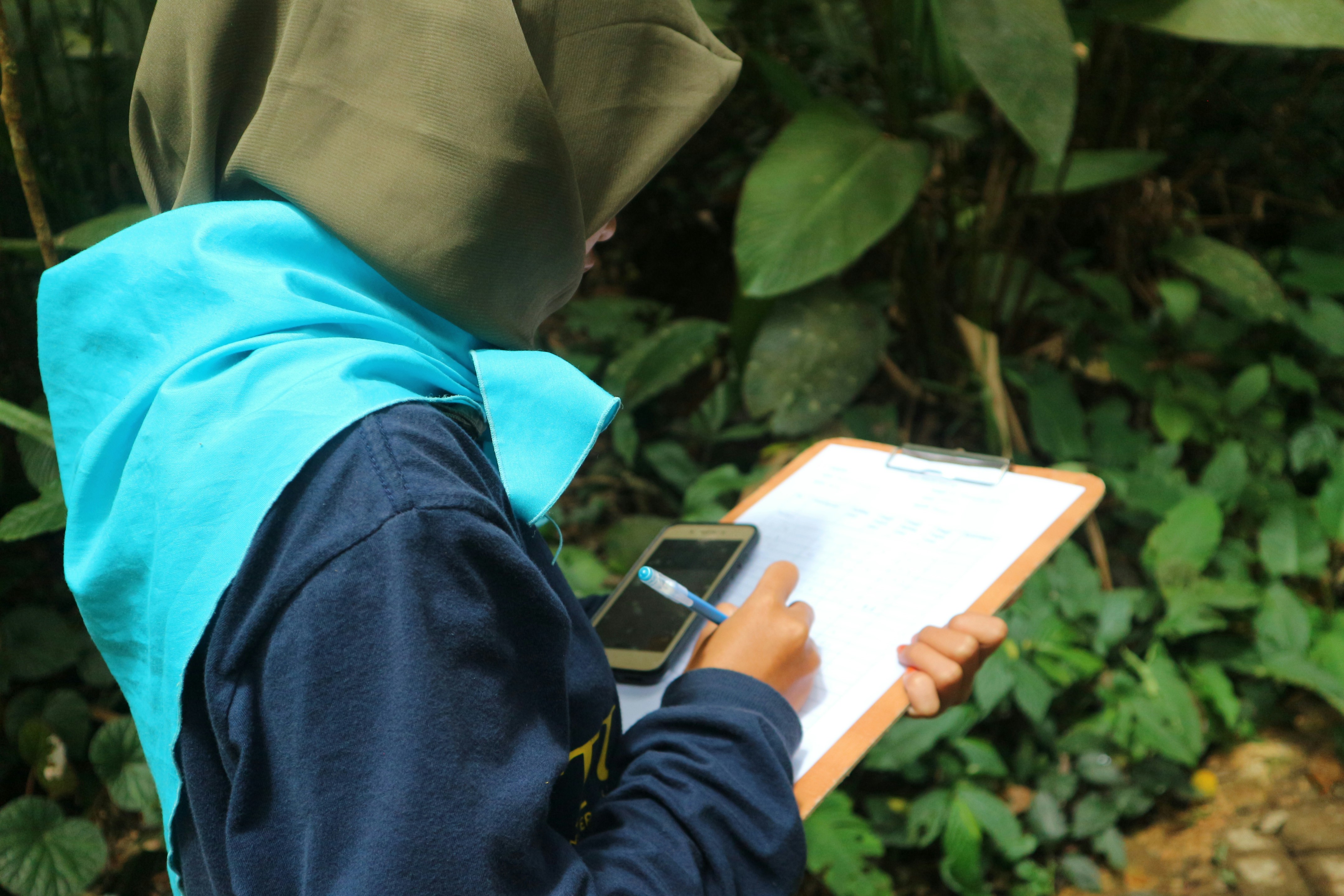 seseorang berjilbab menulis di clipboard