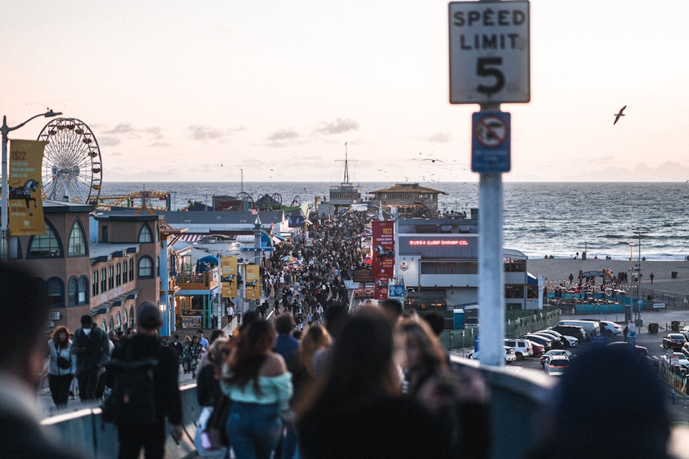 a crowd of people walking down a street next to the ocean