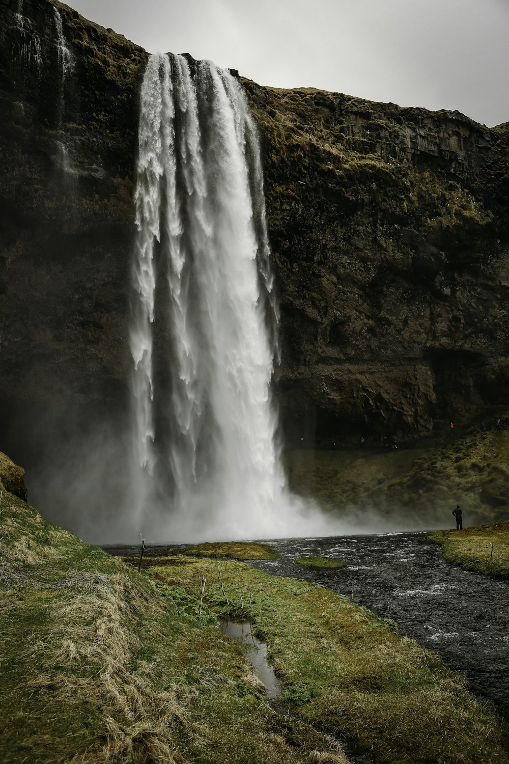 a man standing in front of a tall waterfall