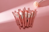Elegant makeup brushes arranged neatly on a soft pink background.