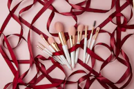 Hands holding delicate makeup brushes dipped in rose gold and white tones.