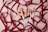A collection of makeup brushes with white handles and rose gold accents is artistically arranged on a light pink surface. They are intertwined with elegant dark red satin ribbons, adding a touch of luxury and sophistication.