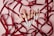 A collection of makeup brushes with white handles and rose gold accents is artistically arranged on a light pink surface. They are intertwined with elegant dark red satin ribbons, adding a touch of luxury and sophistication.