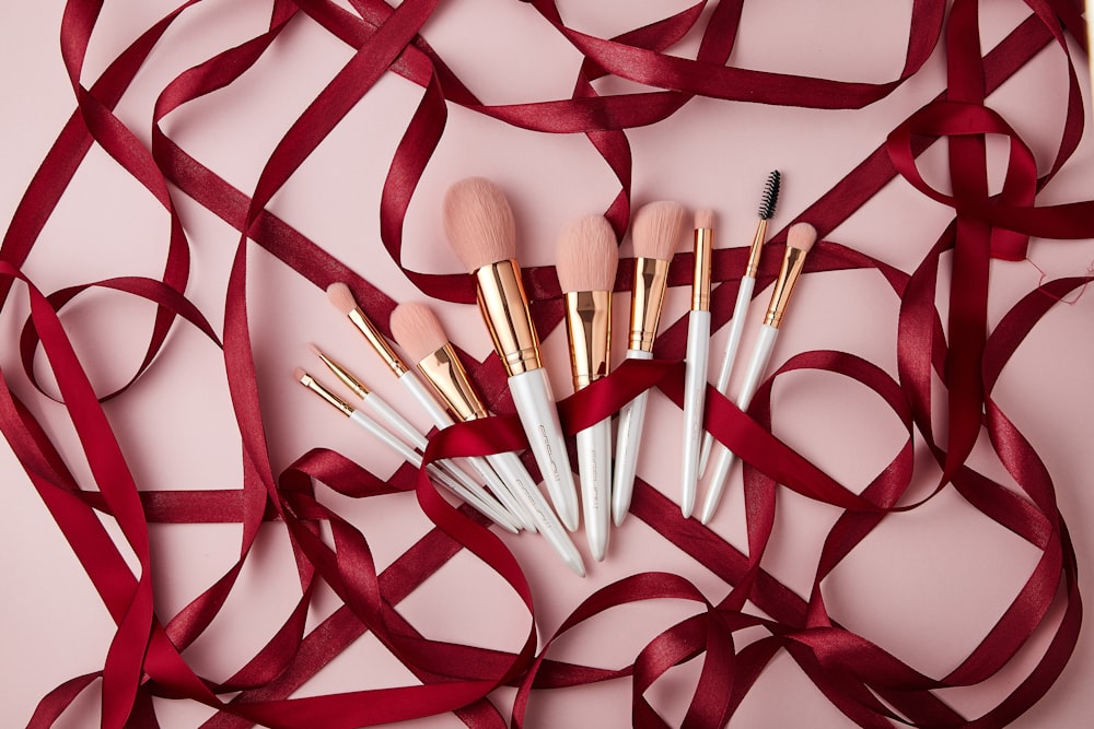 a group of makeup brushes sitting on top of a red ribbon