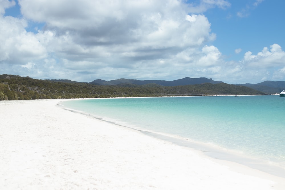 a white sandy beach with a boat in the water