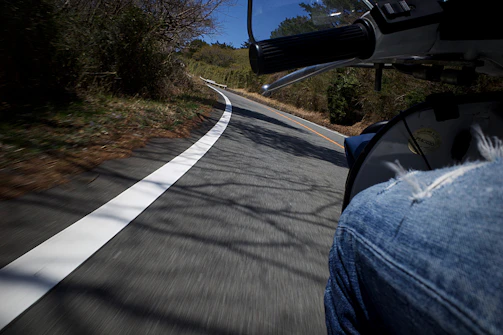 A dynamic shot of a rider leaning into a sharp curve on a winding forest road.