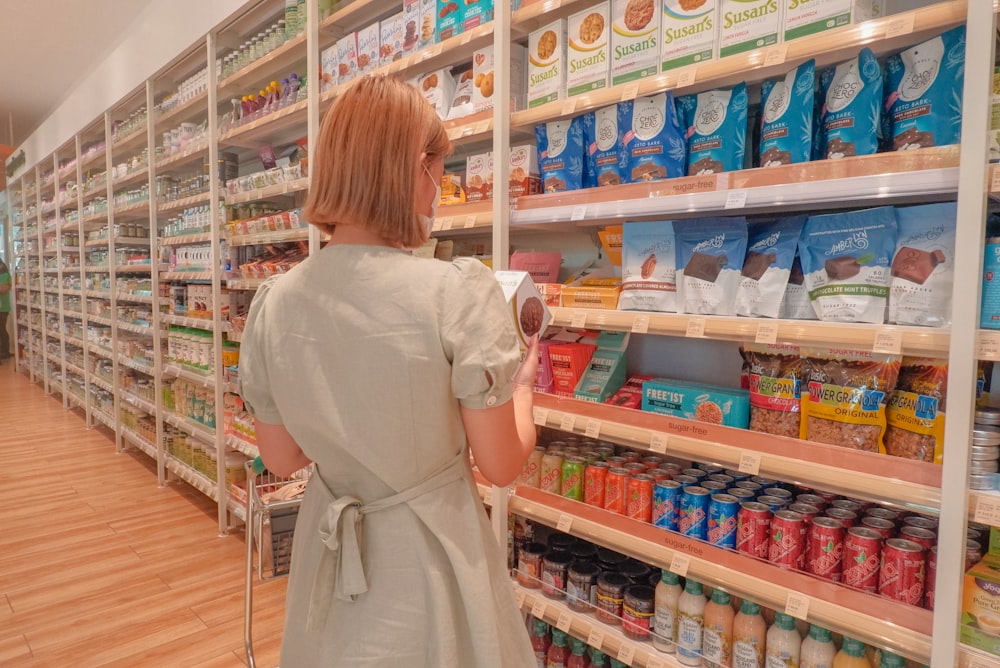a woman in a white dress is looking at a shelf of food