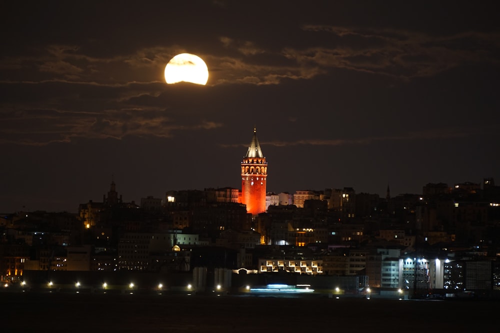 a full moon is seen over a city at night