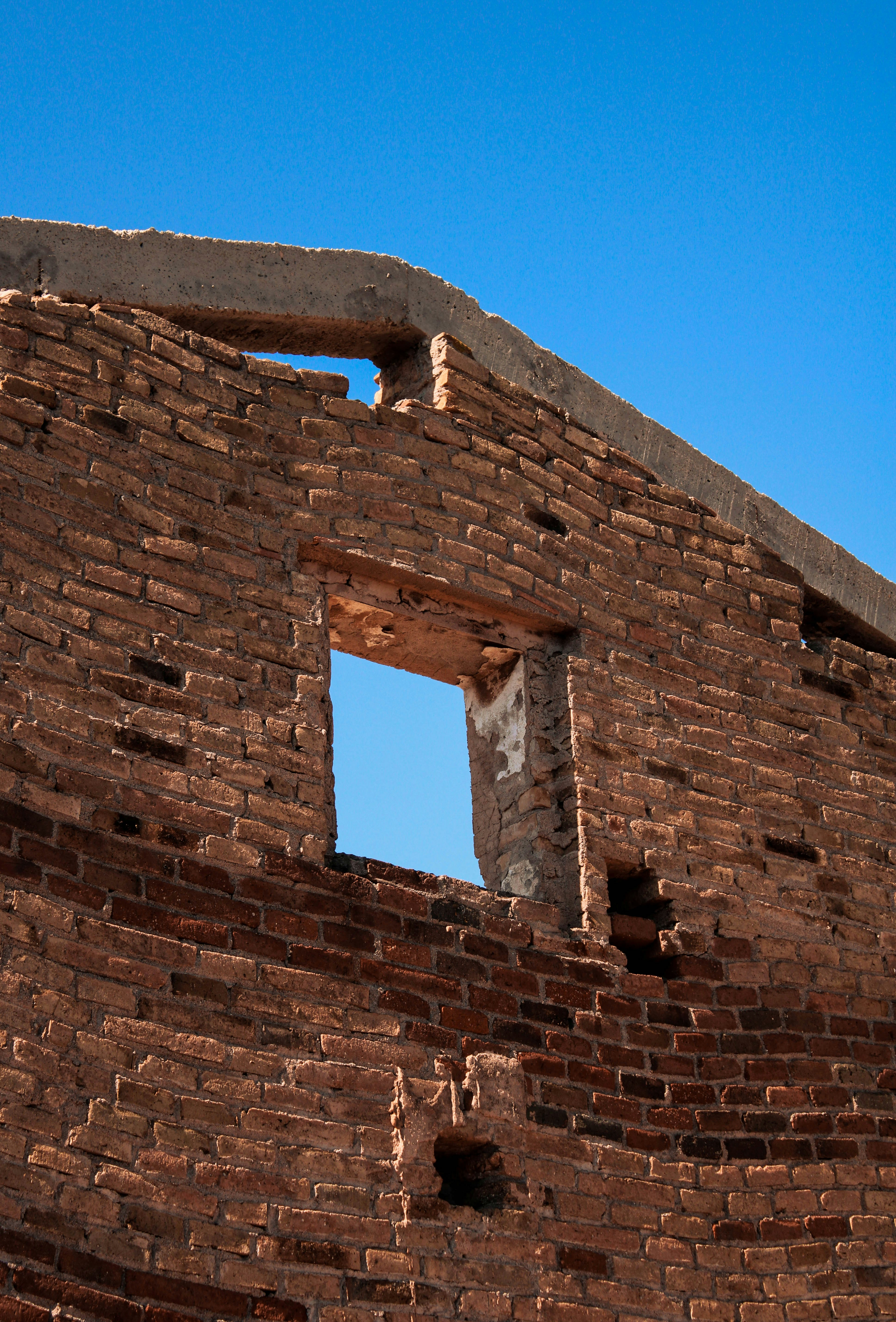 a brick building with a window and a sky background