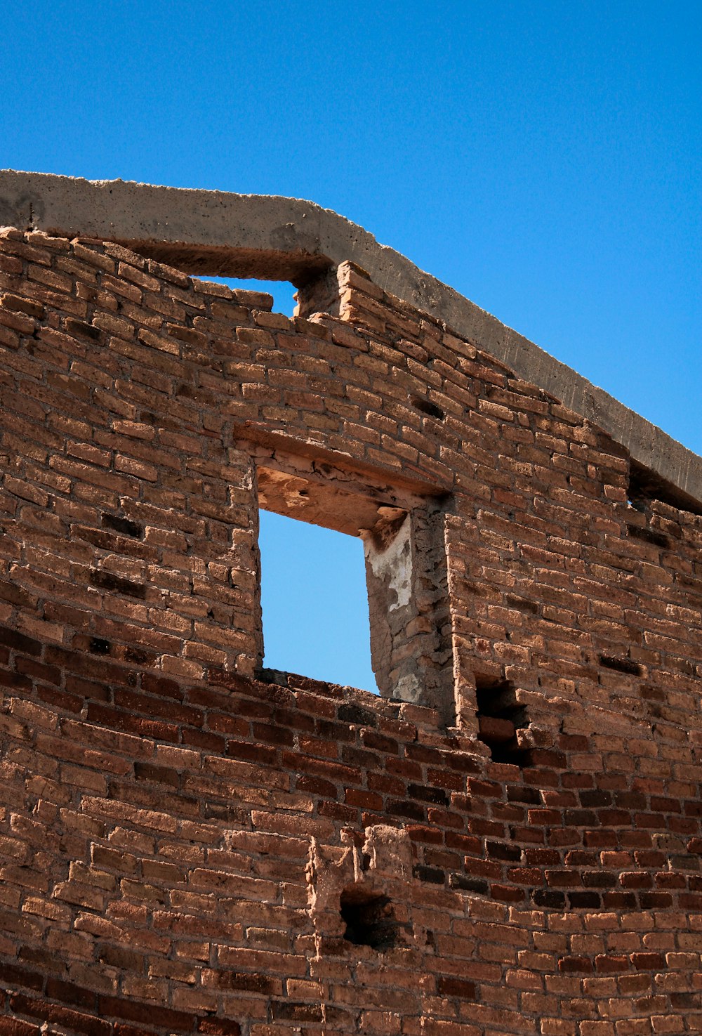 a brick building with a window and a sky background