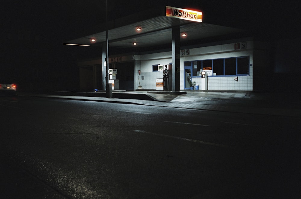 a gas station at night with a car passing by