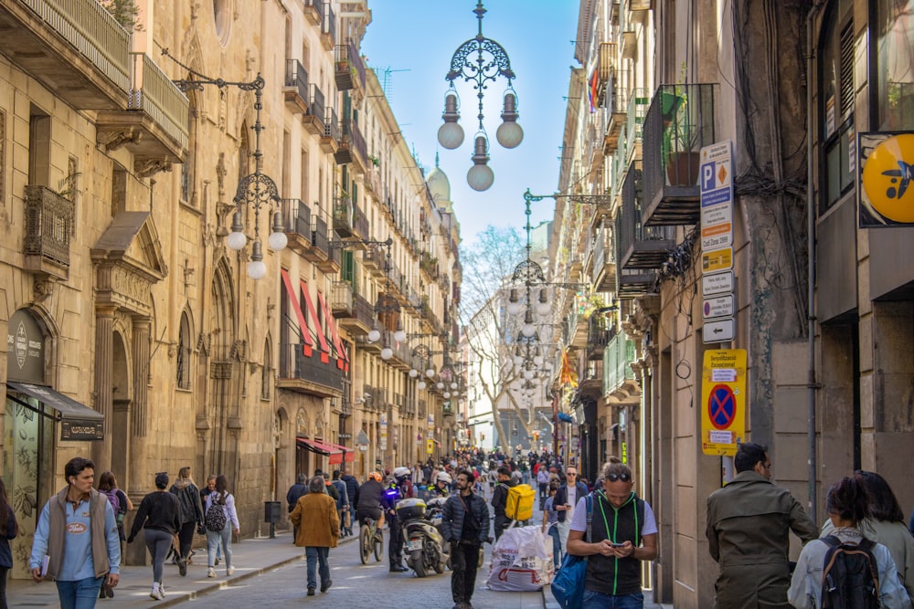 a group of people walking down a street next to tall buildings