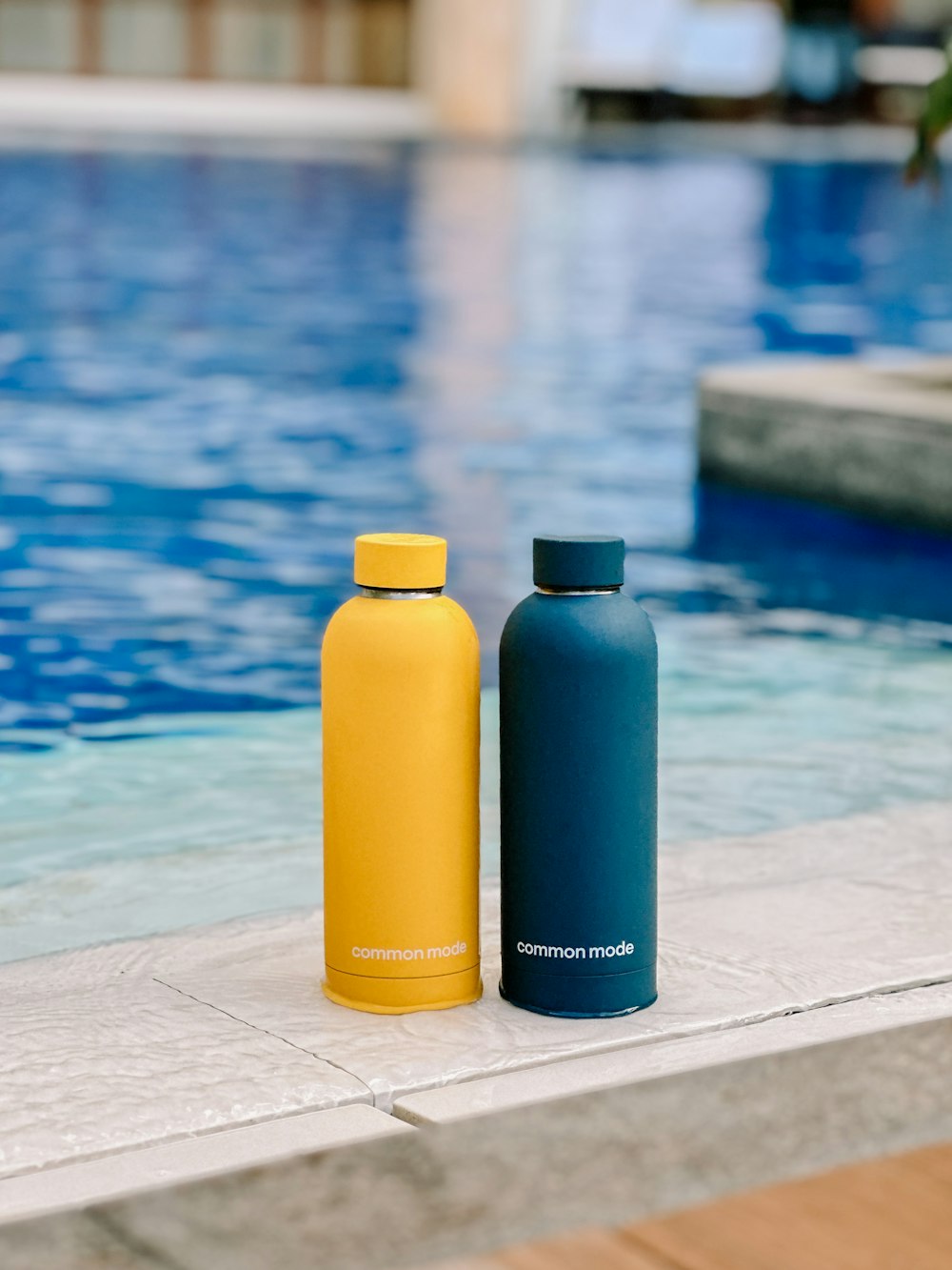 two water bottles sitting next to a swimming pool