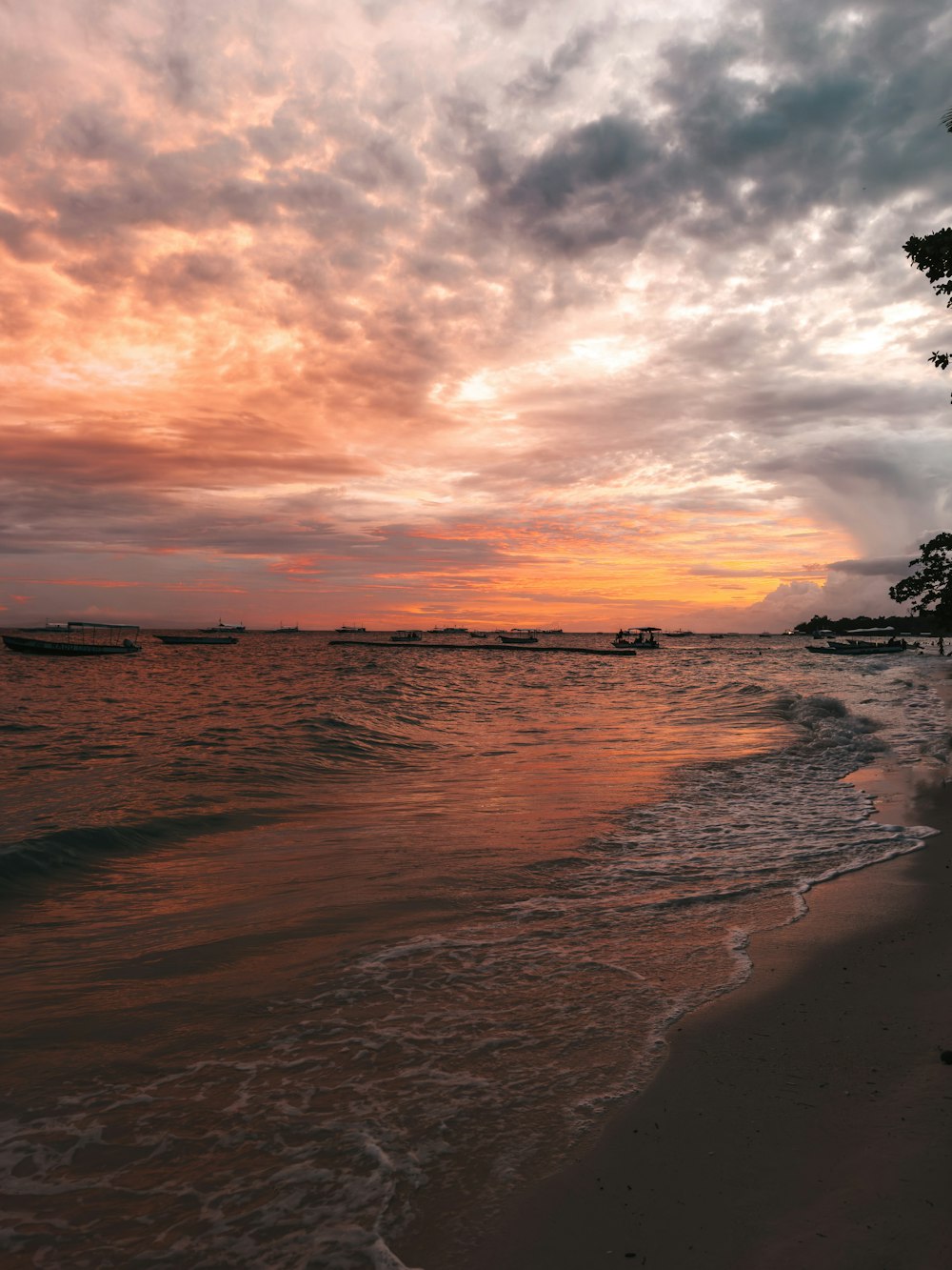 a sunset on a beach with boats in the water