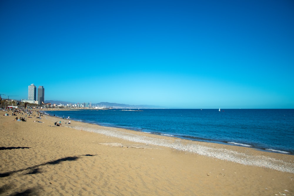 a beach with people walking on it and buildings in the background