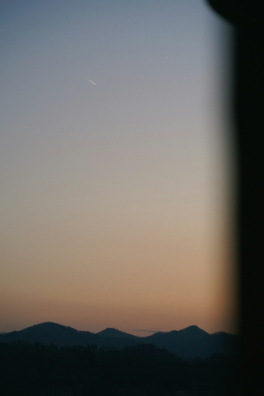 a plane flying in the sky at sunset