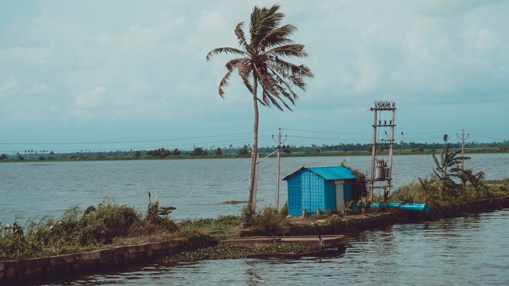 a blue shack sitting on the side of a body of water