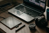 A laptop and camera setup on a rustic wooden table, ready for content creation.