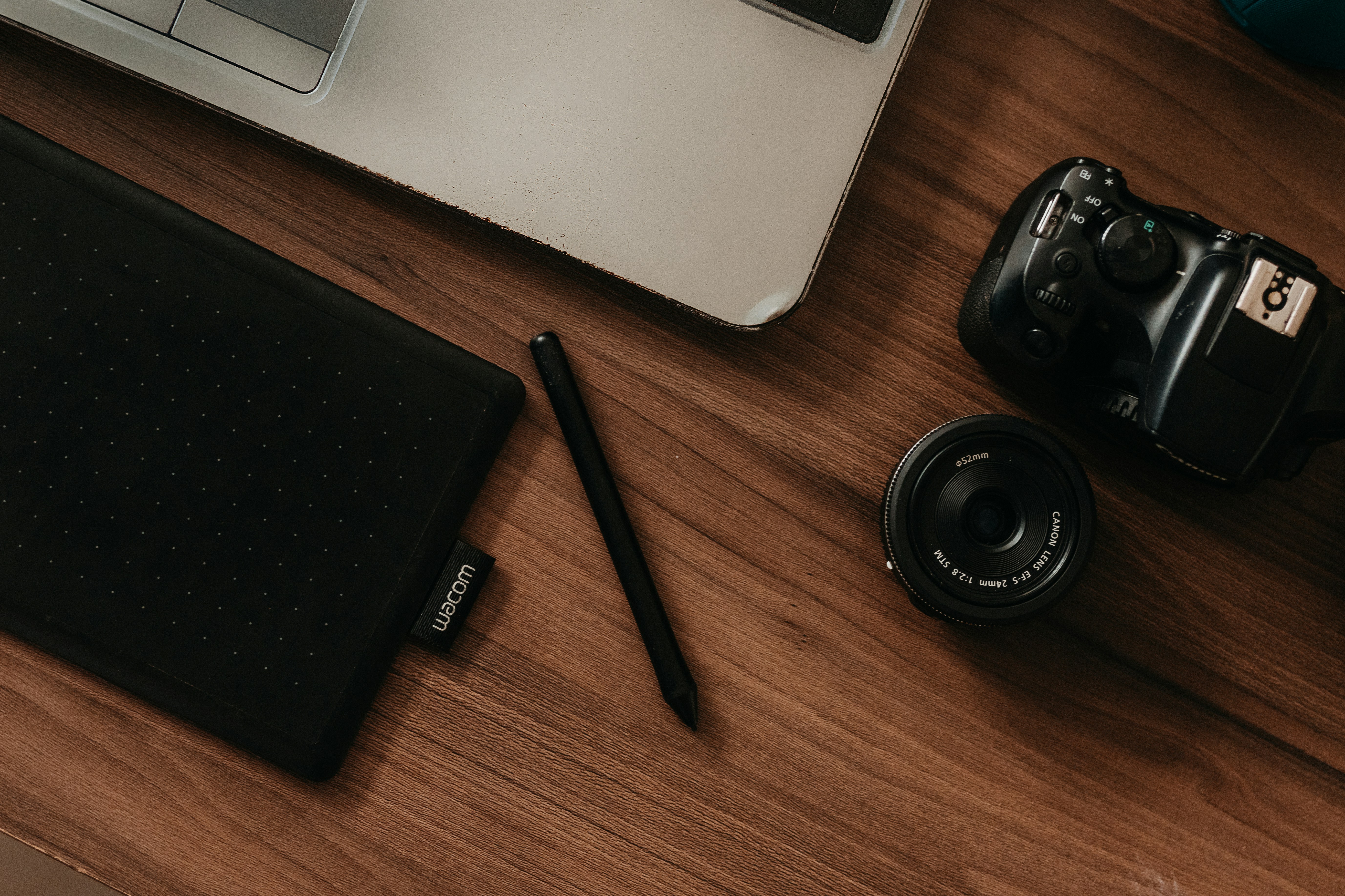a camera, a pen, and a laptop on a desk