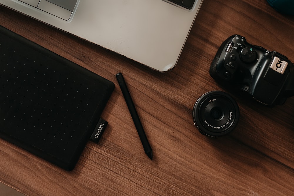 a camera, a pen, and a laptop on a desk