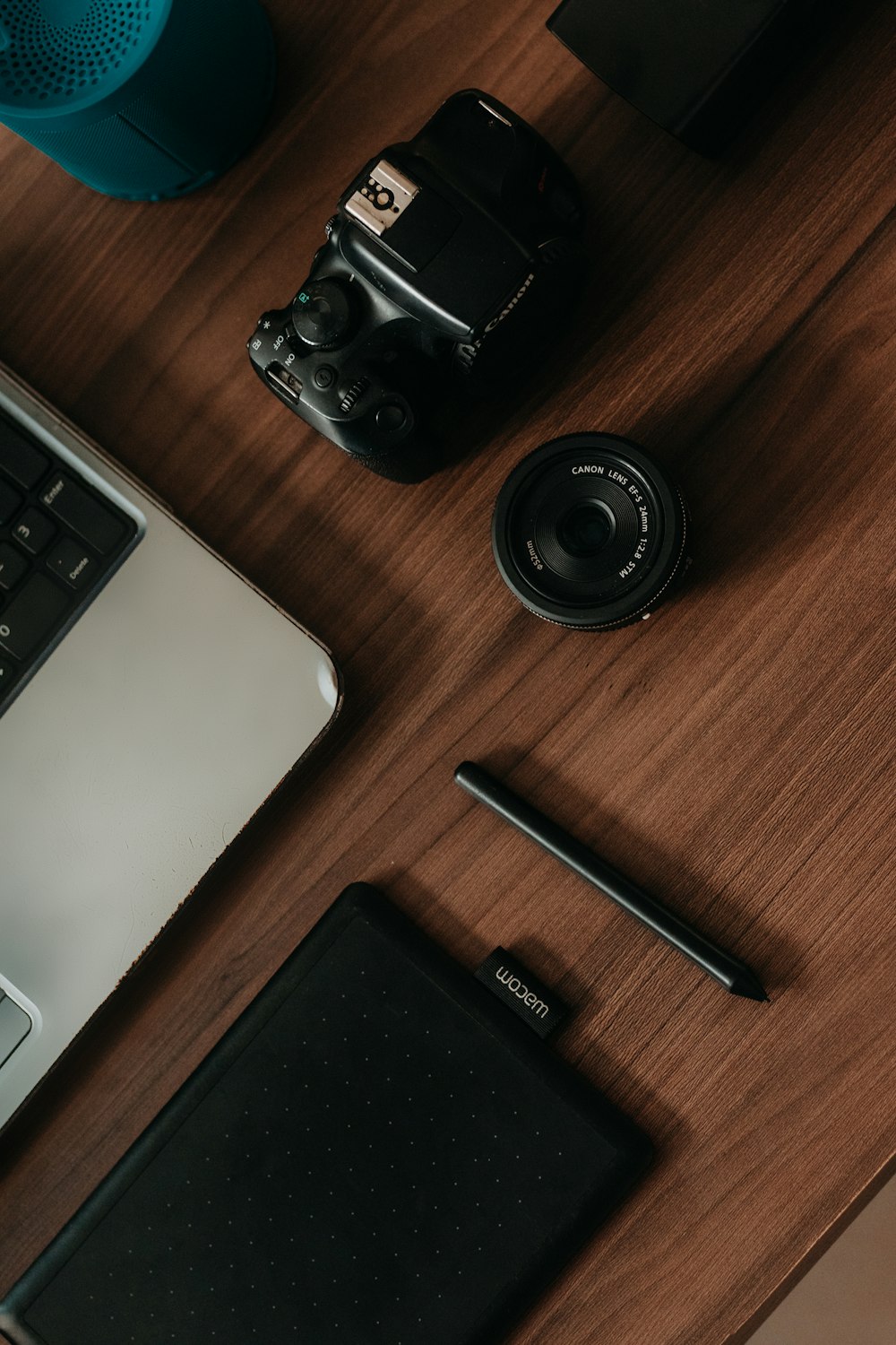 a desk with a laptop a camera and a pen