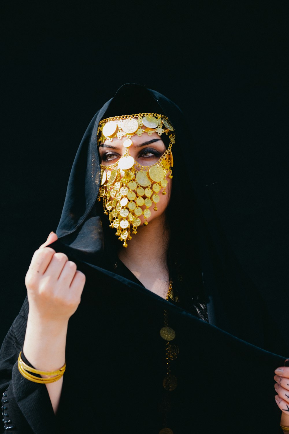 a woman wearing a black veil and a gold mask