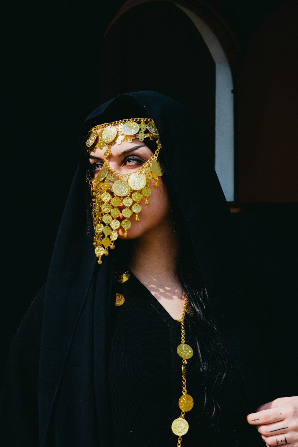 a woman wearing a black veil and gold coins on her face