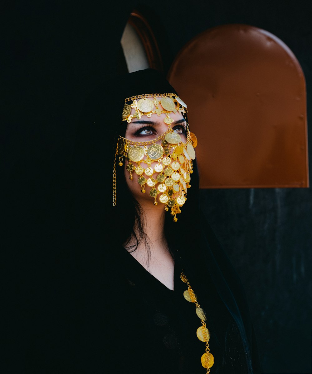 a woman wearing a gold mask and gold jewelry