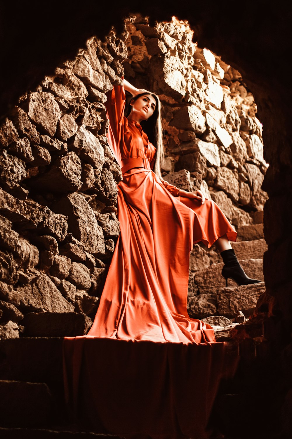 a woman in a long red dress standing in a cave