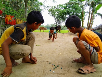 Children playing traditional congklak game outdoors in West Java village