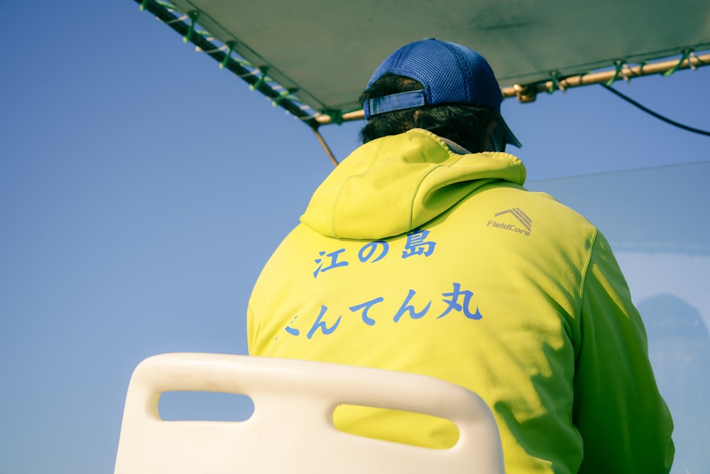 a man in a yellow hoodie sitting on a boat