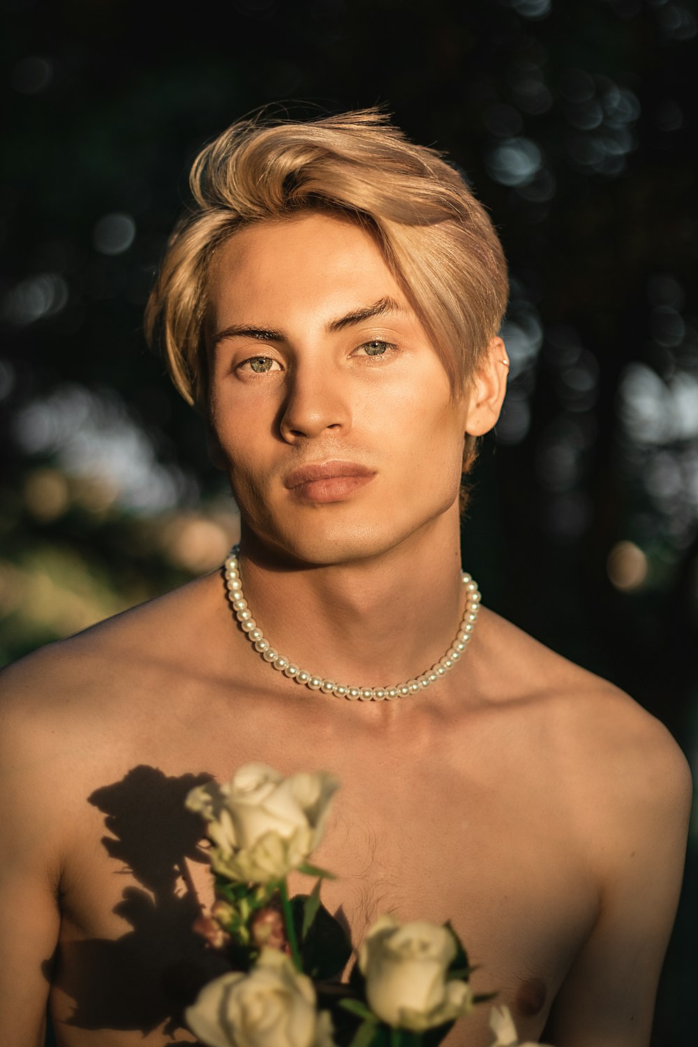 a man with a necklace on his neck holding a bouquet of flowers