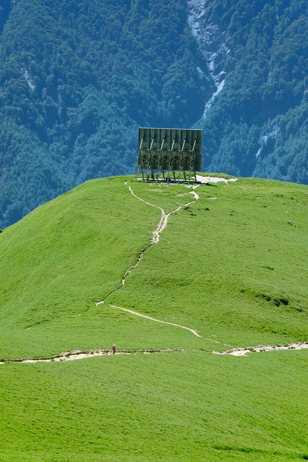 a grassy hill with a wooden structure on top of it