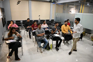 A professional giving a presentation to an audience in a bright, modern classroom.