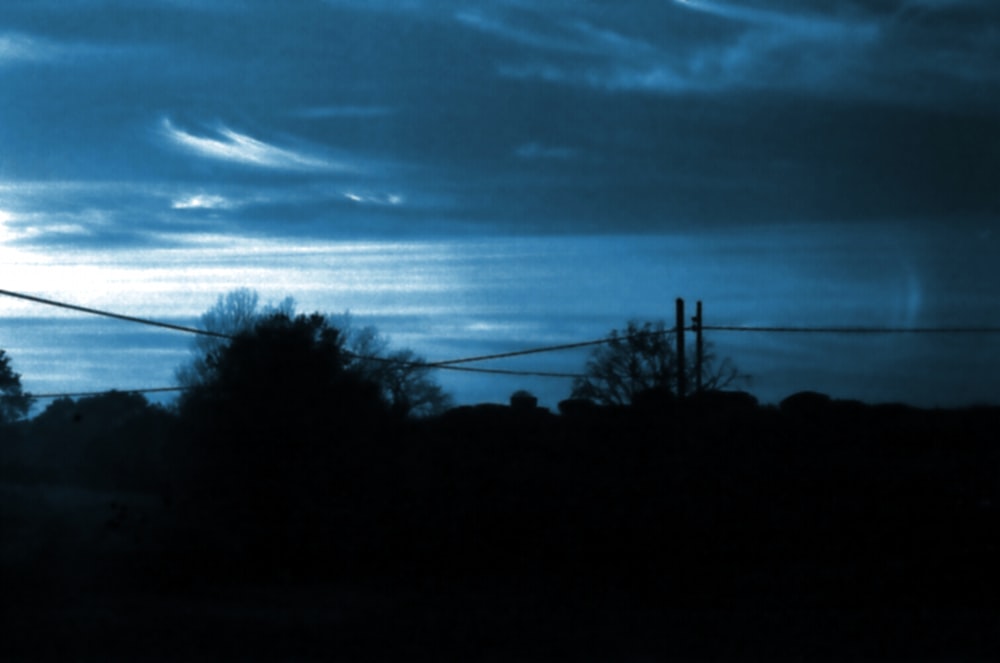 a blue sky with clouds and trees in the foreground