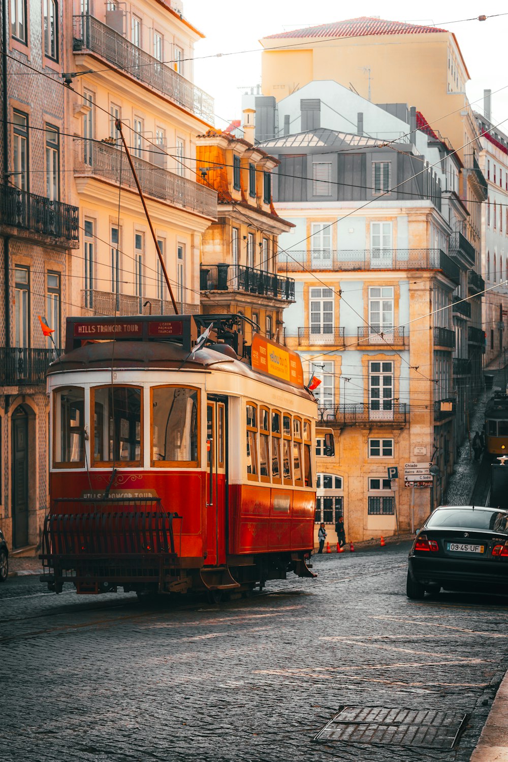 a red trolley car traveling down a street next to tall buildings