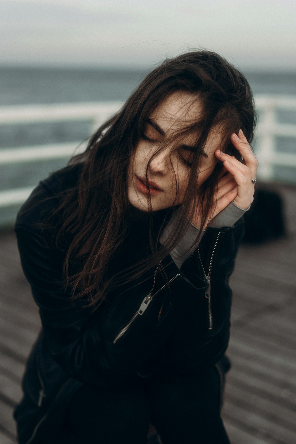 a woman sitting on top of a wooden deck next to the ocean