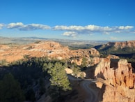 Trail winding through vibrant red and orange rock formations under a clear blue sky.