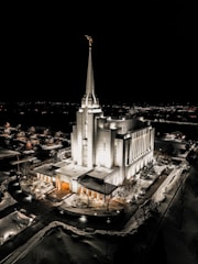 A detailed light-up replica of the Salt Lake Temple glowing warmly on a wooden shelf.
