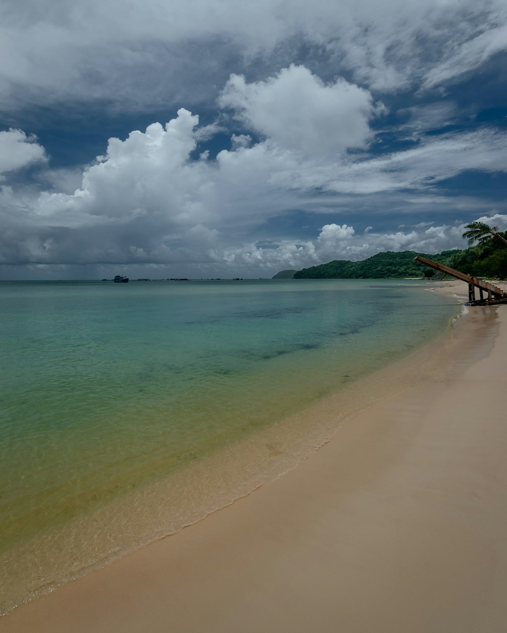 a sandy beach with clear blue water under a cloudy sky